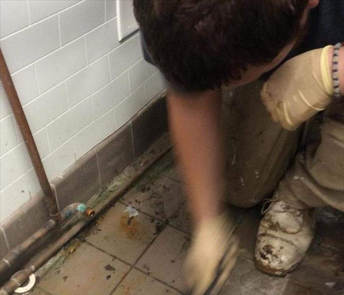 Technician cleaning grease stained tile flooring in restaurant