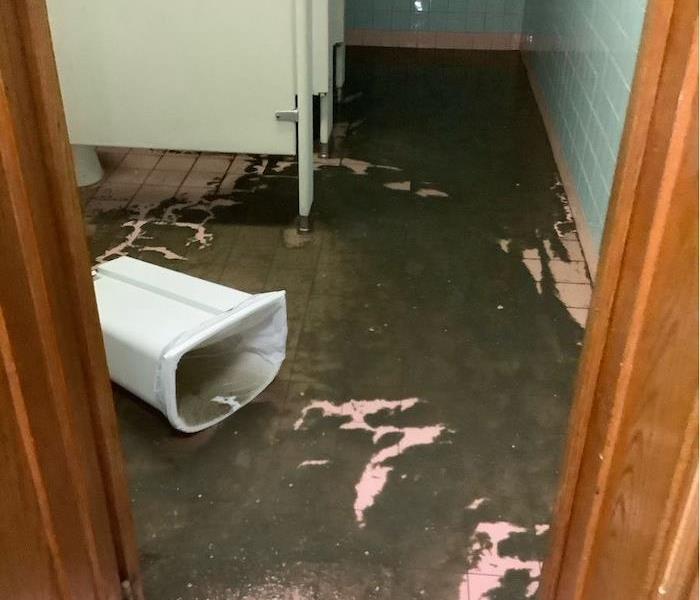 Commercial restroom with trash can in water on the floor