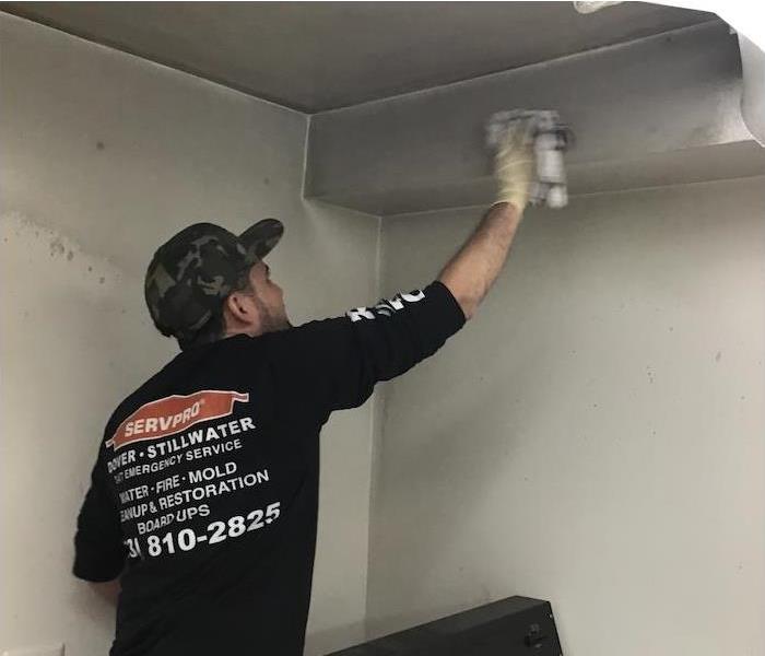 Male employee wiping soot off of drywall in a laundry room
