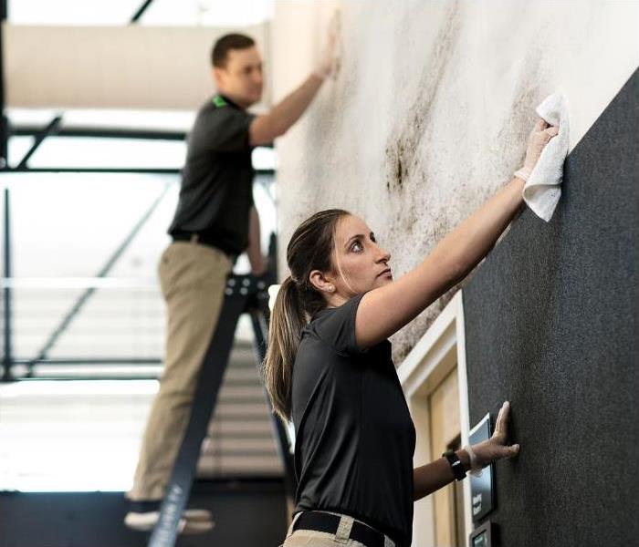 man and woman in SERVPRO gear cleaning a commercial space from fire damage